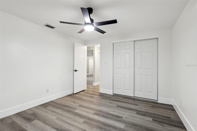 unfurnished bedroom featuring ceiling fan, a closet, and light wood-type flooring