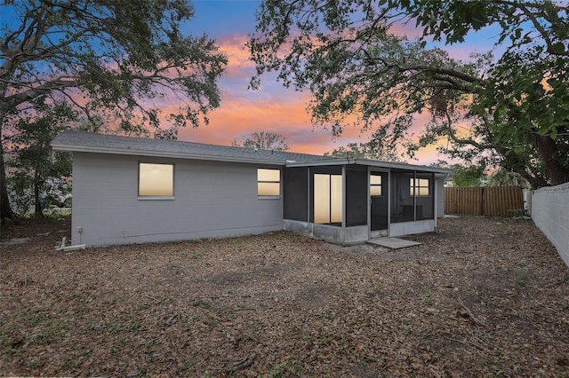 back house at dusk with a sunroom