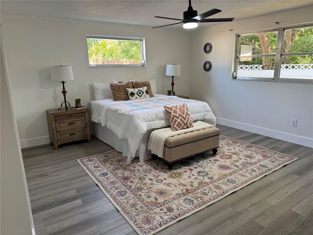 bedroom featuring a textured ceiling, baseboards, ceiling fan, and wood finished floors
