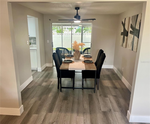 dining space with baseboards, a ceiling fan, and dark wood-style floors