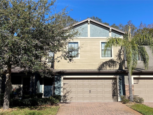 view of front of house featuring decorative driveway, an attached garage, and stucco siding