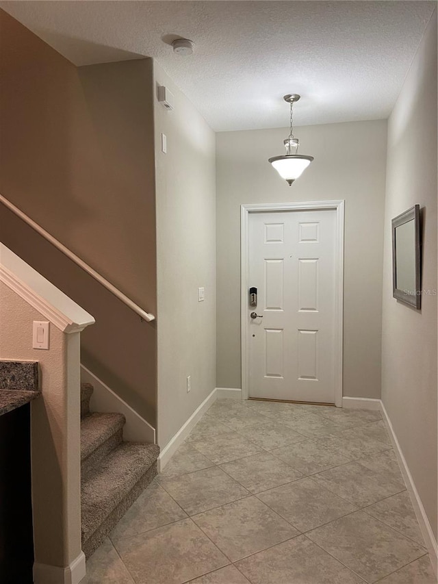 foyer with light tile patterned flooring and a textured ceiling