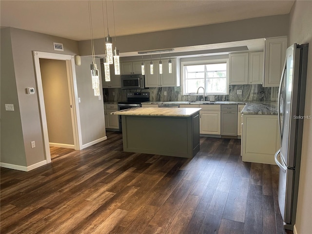 kitchen with dark hardwood / wood-style floors, decorative light fixtures, a kitchen island, appliances with stainless steel finishes, and sink