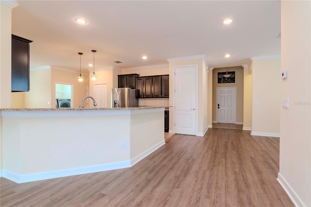 kitchen featuring washer / dryer, light hardwood / wood-style floors, stainless steel refrigerator with ice dispenser, crown molding, and light stone counters