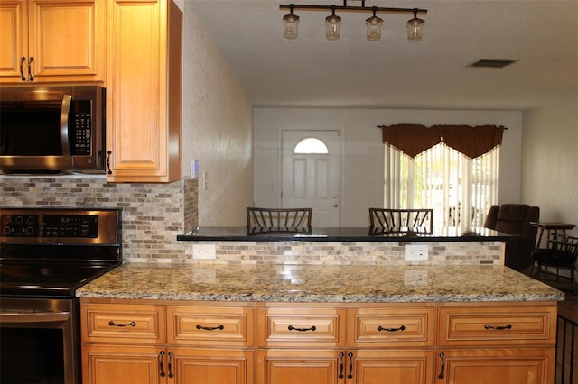 kitchen featuring light stone countertops, appliances with stainless steel finishes, and tasteful backsplash