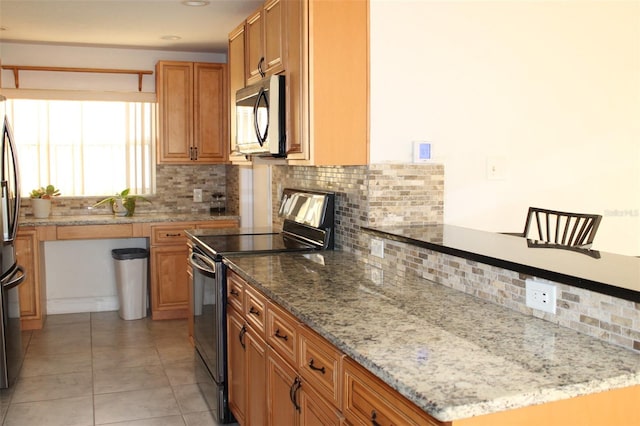 kitchen with decorative backsplash, light tile patterned floors, light stone countertops, and appliances with stainless steel finishes