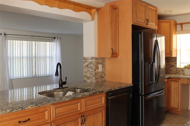 kitchen with light stone countertops, dishwasher, sink, tasteful backsplash, and stainless steel refrigerator with ice dispenser