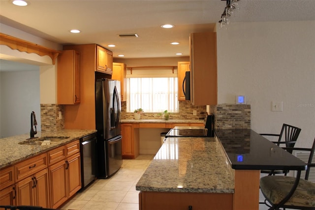 kitchen with light stone countertops, a kitchen breakfast bar, backsplash, black appliances, and sink