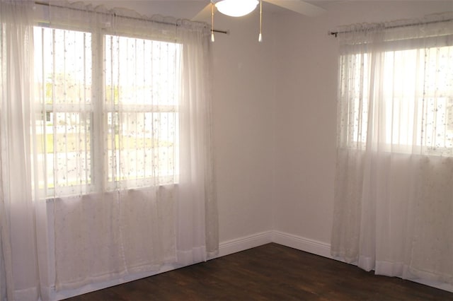 empty room featuring ceiling fan, plenty of natural light, and dark hardwood / wood-style floors