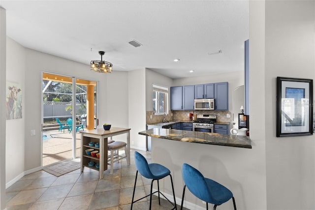 kitchen featuring kitchen peninsula, pendant lighting, stainless steel appliances, tasteful backsplash, and a breakfast bar area