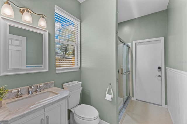 bathroom featuring a shower with door, vanity, and toilet