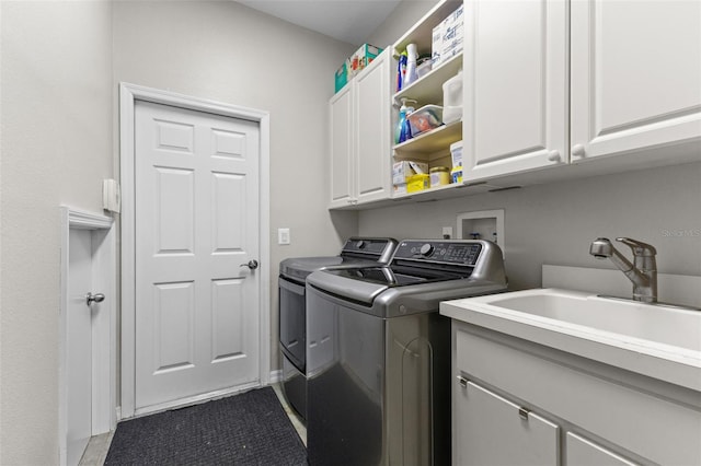 laundry area with separate washer and dryer, cabinets, and sink