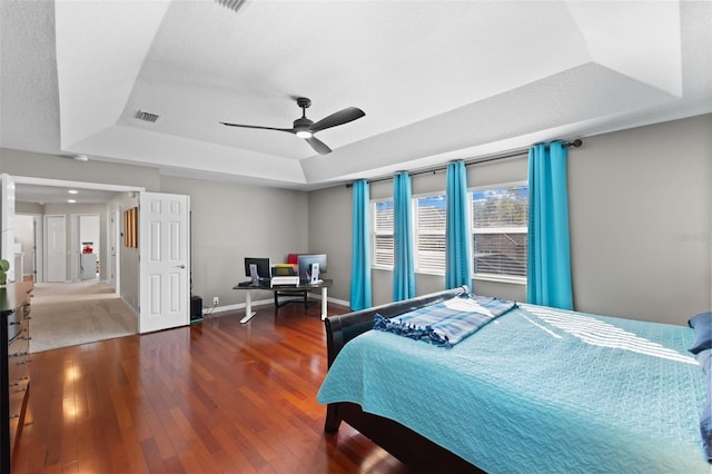 bedroom with ceiling fan, a raised ceiling, and dark hardwood / wood-style floors