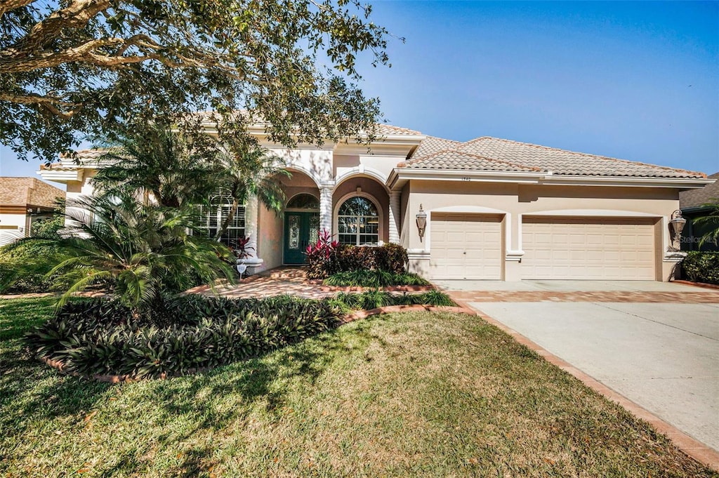 mediterranean / spanish house with a garage and a front lawn