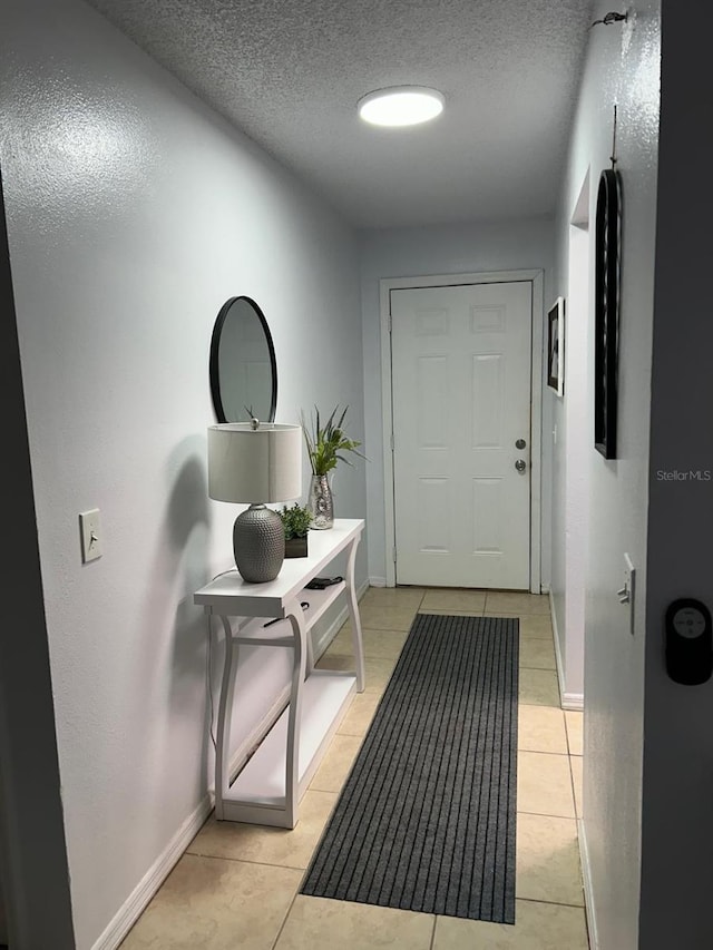 entryway with light tile patterned floors and a textured ceiling