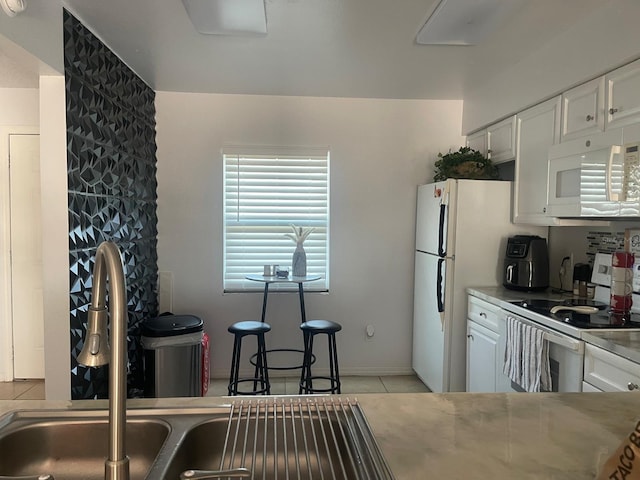 kitchen featuring light tile patterned floors, white cabinets, white appliances, and sink