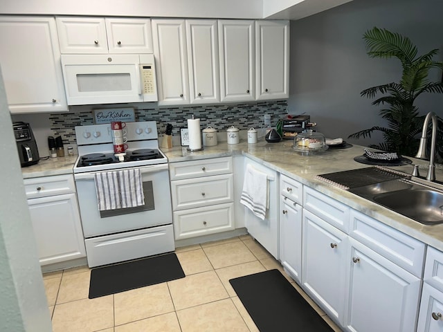 kitchen with light tile patterned floors, white appliances, white cabinetry, and sink