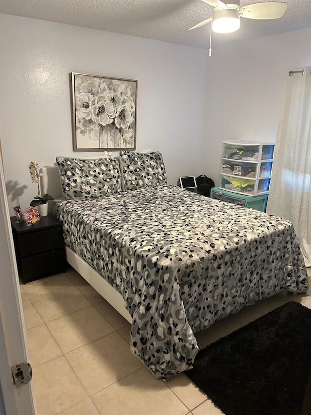 bedroom with a textured ceiling, ceiling fan, and light tile patterned flooring