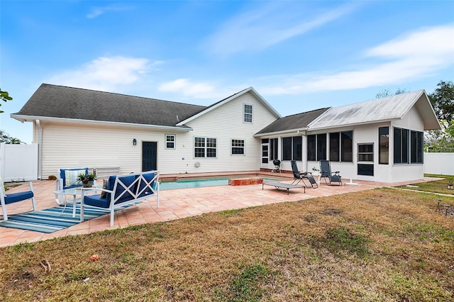 rear view of house featuring fence, a yard, an outdoor pool, a sunroom, and a patio area