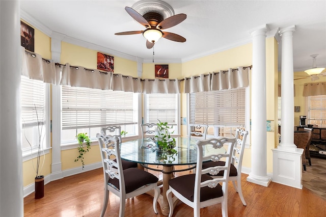 dining space featuring ornamental molding, wood finished floors, a ceiling fan, and decorative columns