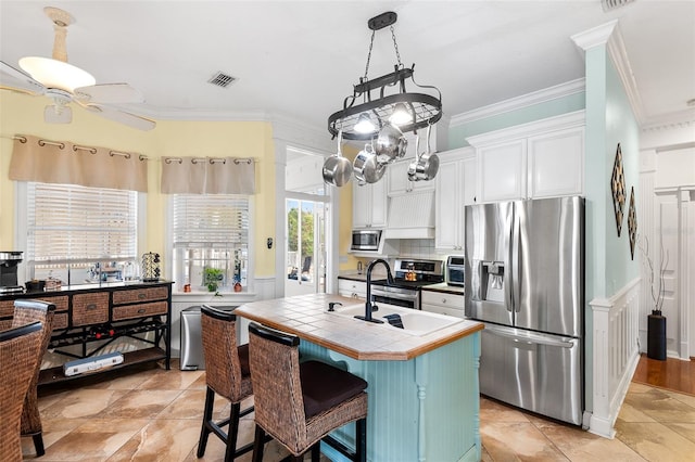 kitchen with visible vents, white cabinetry, tile countertops, appliances with stainless steel finishes, and crown molding