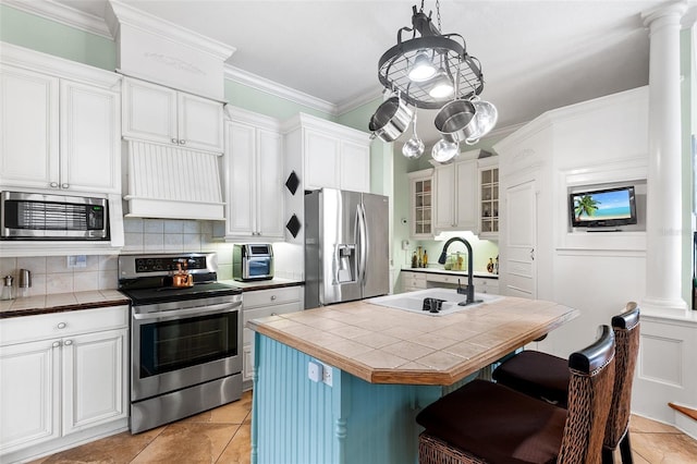 kitchen with tile countertops, custom exhaust hood, a sink, stainless steel appliances, and crown molding