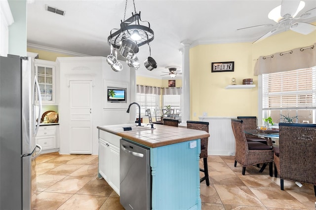 kitchen featuring visible vents, a sink, stainless steel appliances, crown molding, and tile counters