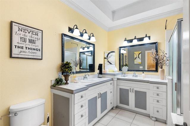 full bathroom with toilet, two vanities, ornamental molding, and a sink