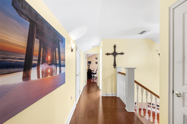 hall featuring visible vents, baseboards, vaulted ceiling, wood-type flooring, and an upstairs landing