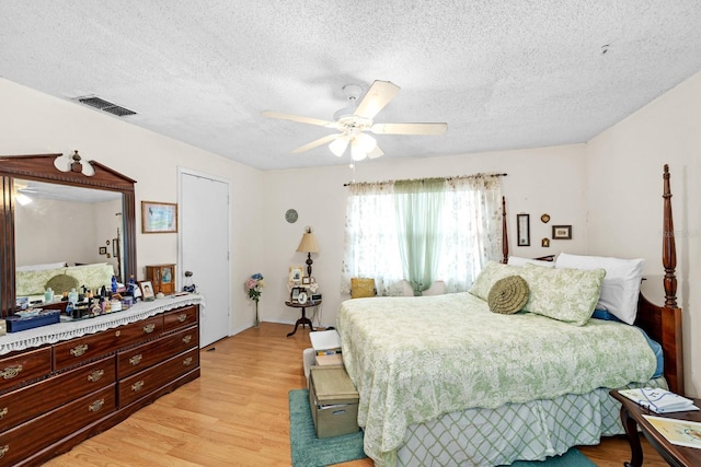 bedroom with ceiling fan, light hardwood / wood-style floors, and a textured ceiling