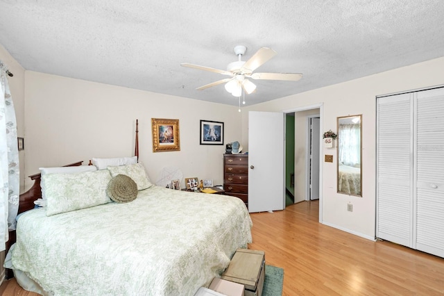 bedroom with a closet, ceiling fan, light hardwood / wood-style floors, and a textured ceiling