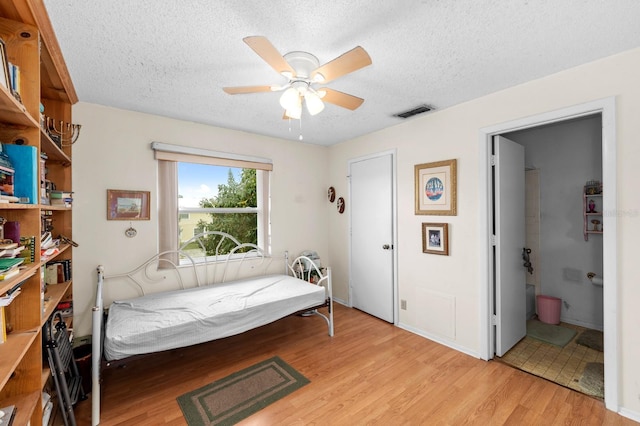 bedroom with ceiling fan, light hardwood / wood-style floors, and a textured ceiling