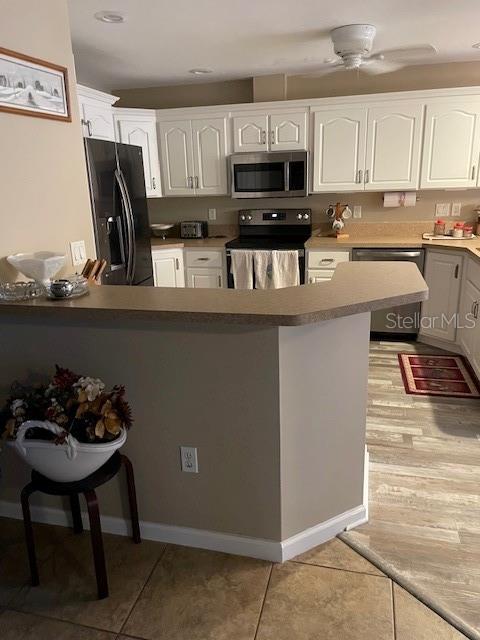 kitchen with ceiling fan, white cabinetry, stainless steel appliances, and light tile patterned floors