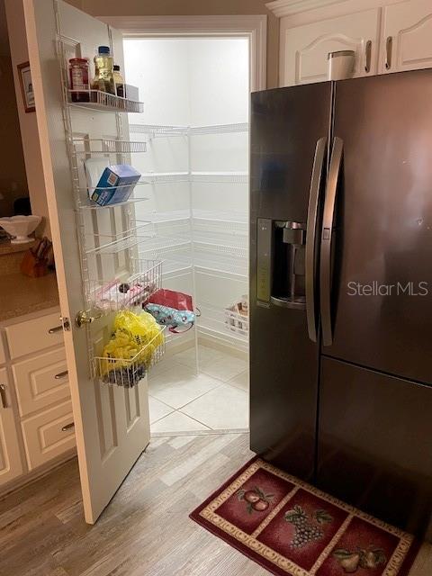 kitchen featuring white cabinets, black fridge, and light wood-type flooring