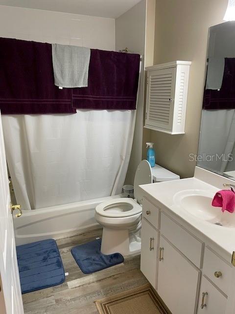 full bathroom featuring shower / bath combination with curtain, vanity, wood-type flooring, and toilet