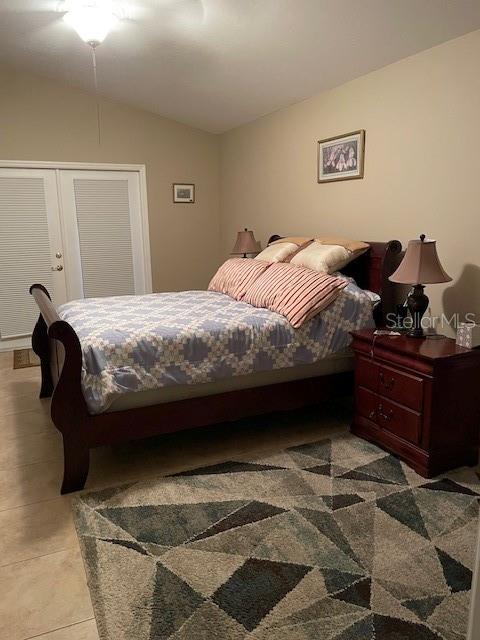 tiled bedroom with french doors and vaulted ceiling