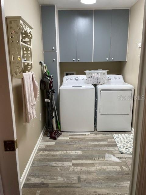 washroom featuring light hardwood / wood-style floors, cabinets, and separate washer and dryer