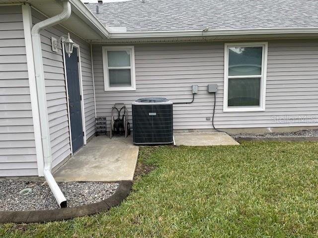 view of side of home with a lawn, cooling unit, and a patio area