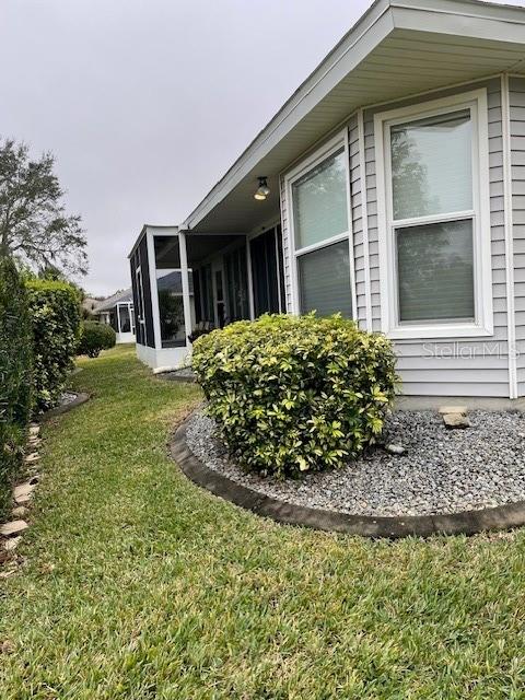 view of property exterior with a lawn and a sunroom