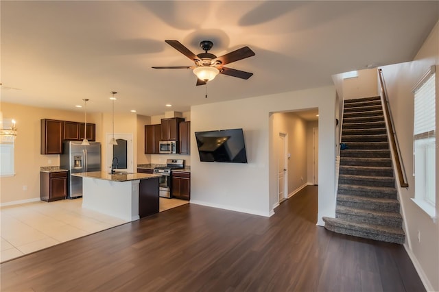 kitchen with a center island with sink, ceiling fan, appliances with stainless steel finishes, decorative light fixtures, and sink