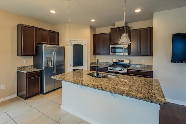 kitchen featuring dark brown cabinetry, stainless steel appliances, sink, a kitchen breakfast bar, and a center island with sink