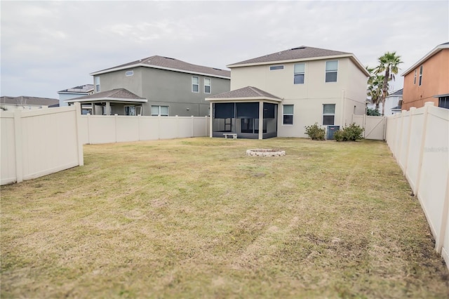 rear view of property with a sunroom, a fire pit, a yard, and central air condition unit