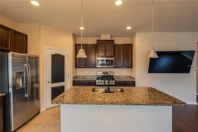 kitchen featuring hanging light fixtures, a kitchen island with sink, light stone counters, and stainless steel appliances