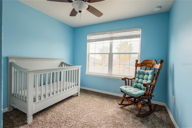 carpeted bedroom featuring ceiling fan and a nursery area