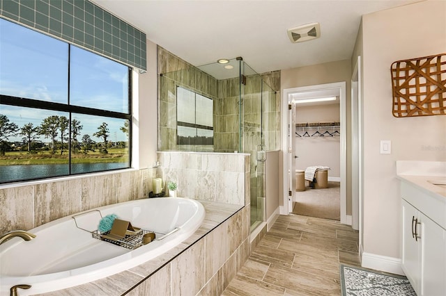 bathroom with plus walk in shower, vanity, and a water view