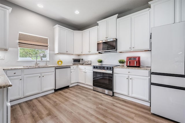 kitchen featuring light hardwood / wood-style floors, stainless steel appliances, light stone countertops, sink, and white cabinetry