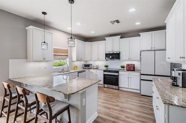 kitchen featuring decorative light fixtures, white cabinets, appliances with stainless steel finishes, and sink