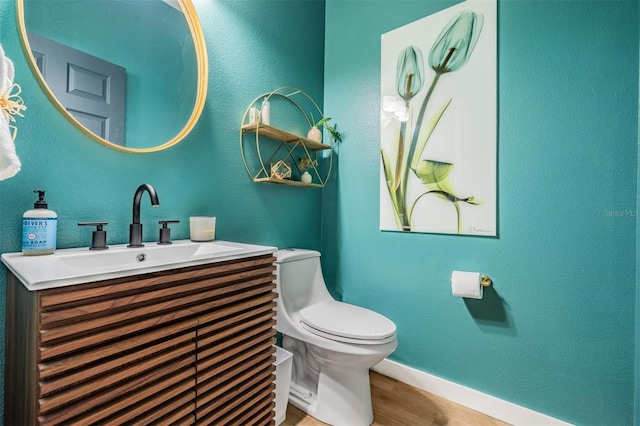 bathroom with toilet, hardwood / wood-style floors, and vanity