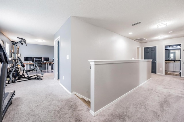 hallway with light colored carpet and a textured ceiling