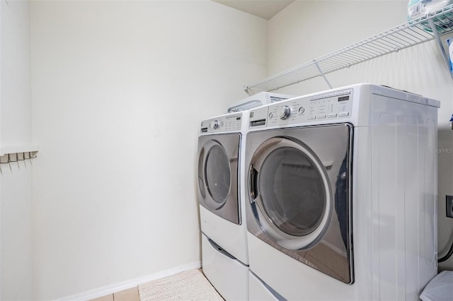 laundry room featuring light tile patterned flooring and washing machine and clothes dryer